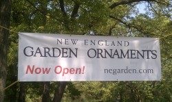 New England Garden Ornaments Sign strung between trees